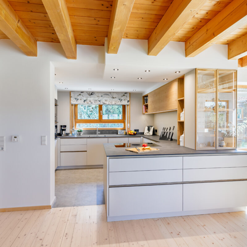 Einladend - Küche<br/> Einbauelemente mit weißer Beschichtung, kombiniert mit massivem Holz